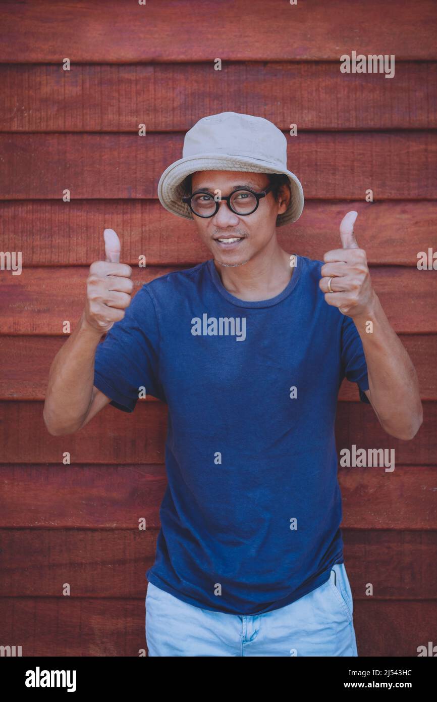 asian man sign good thumb with funny face against old wooden background Stock Photo