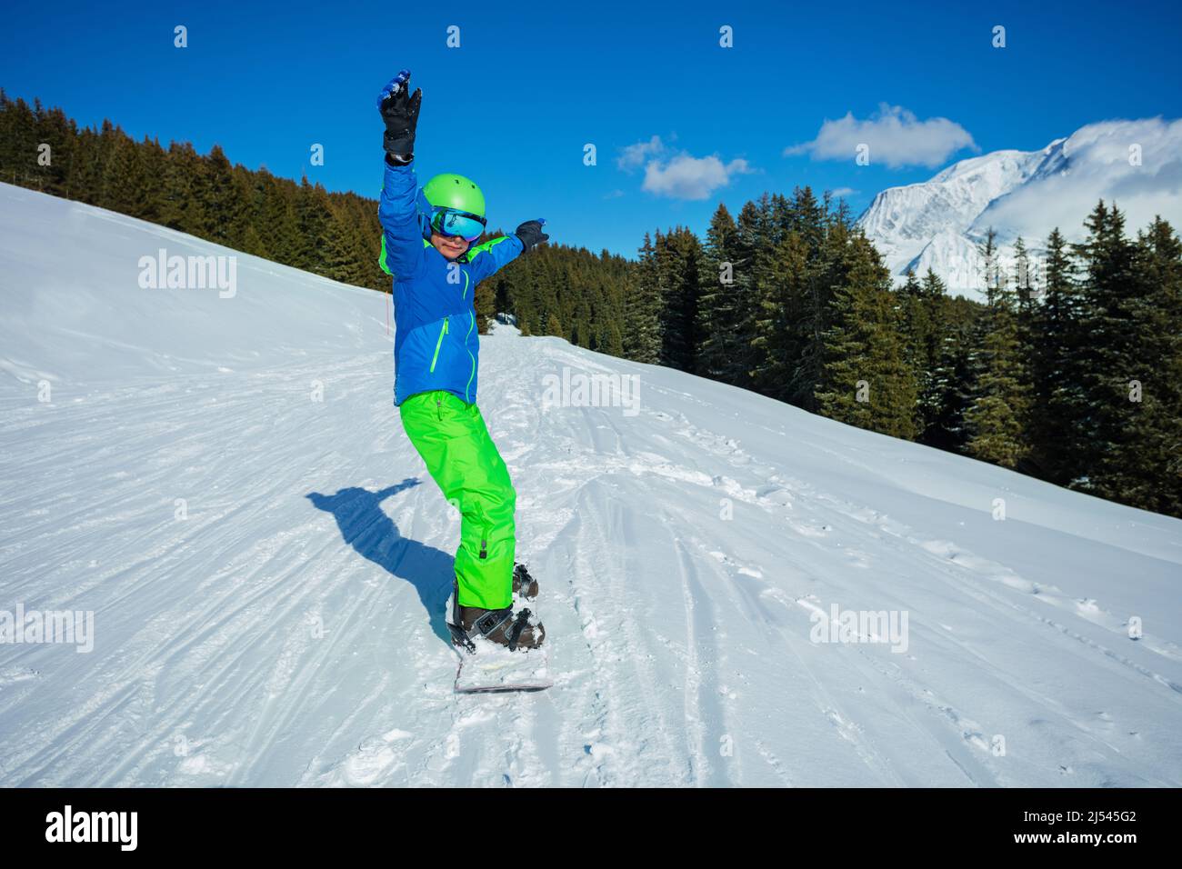Boy slide fast on snowboard from the mountain, front view Stock Photo