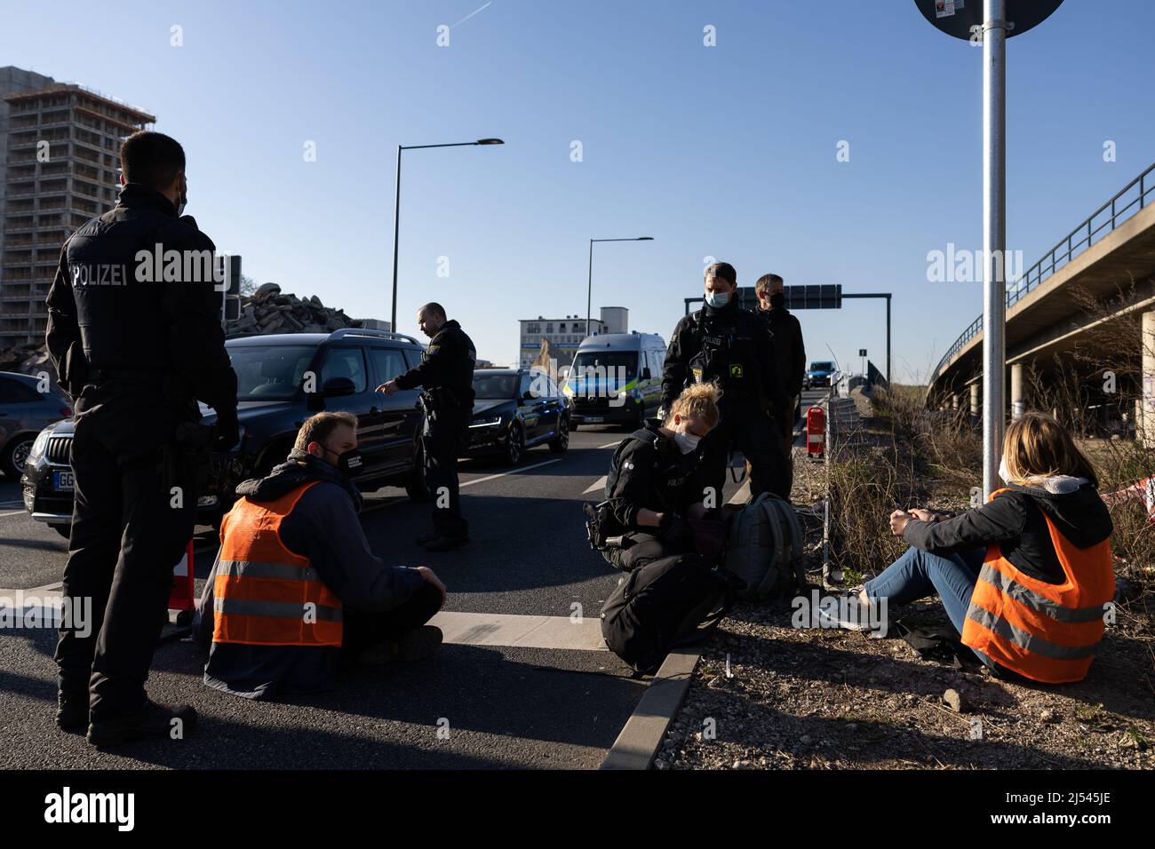 Offenbach, Germany. 20th Apr, 2022. An activist has stuck his hand on the roadway in protest, which is why the police have to regulate traffic around the activist. Activists of the "Last Generation" blocked the highway exit in Offenbach-Kaiserlei. Credit: Hannes P. Albert/dpa/Alamy Live News Stock Photo