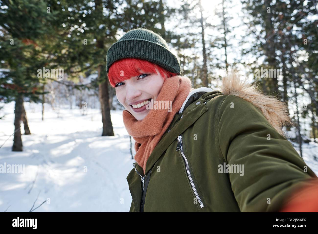 Portrait of joyful gen Z Caucasian girl with red hair taking selfie photo outdoors on winter day smiling at camera Stock Photo
