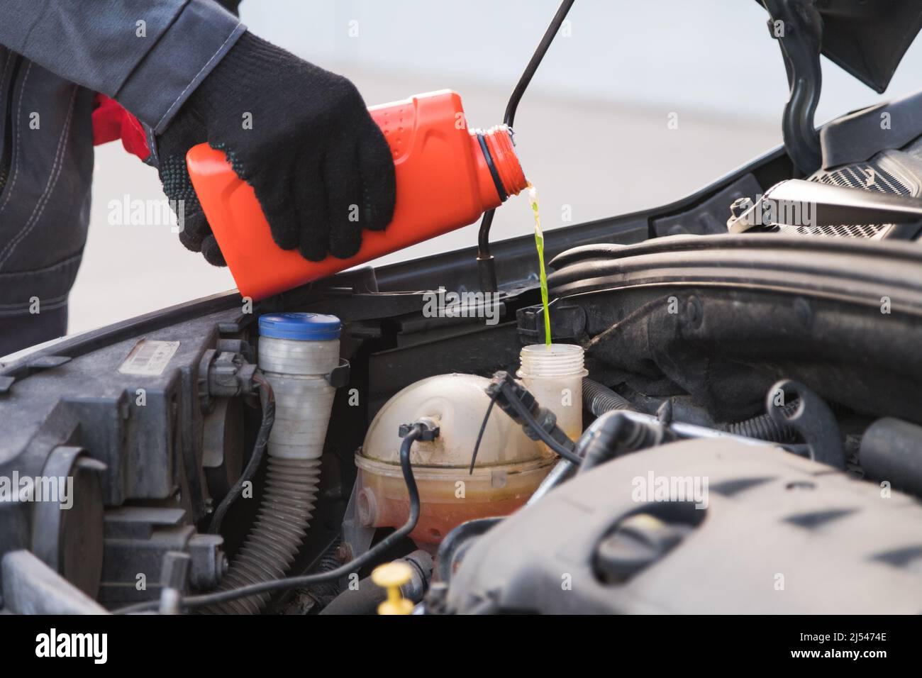 Car master mechanic pouring antifreeze into expansion tank at car service workshop Stock Photo