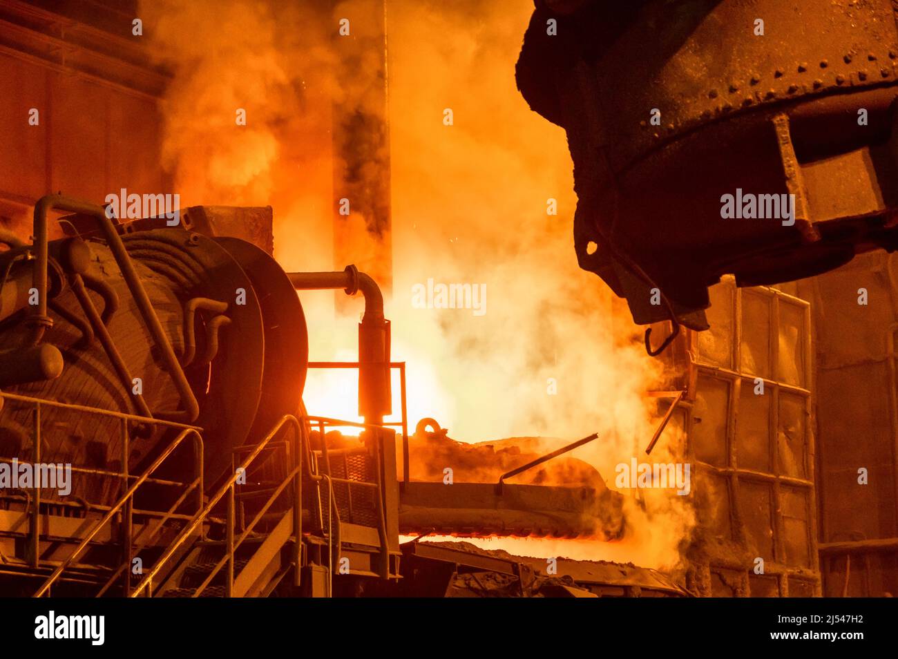 Electric arc furnace during operation. Lots of smoke and fire Stock