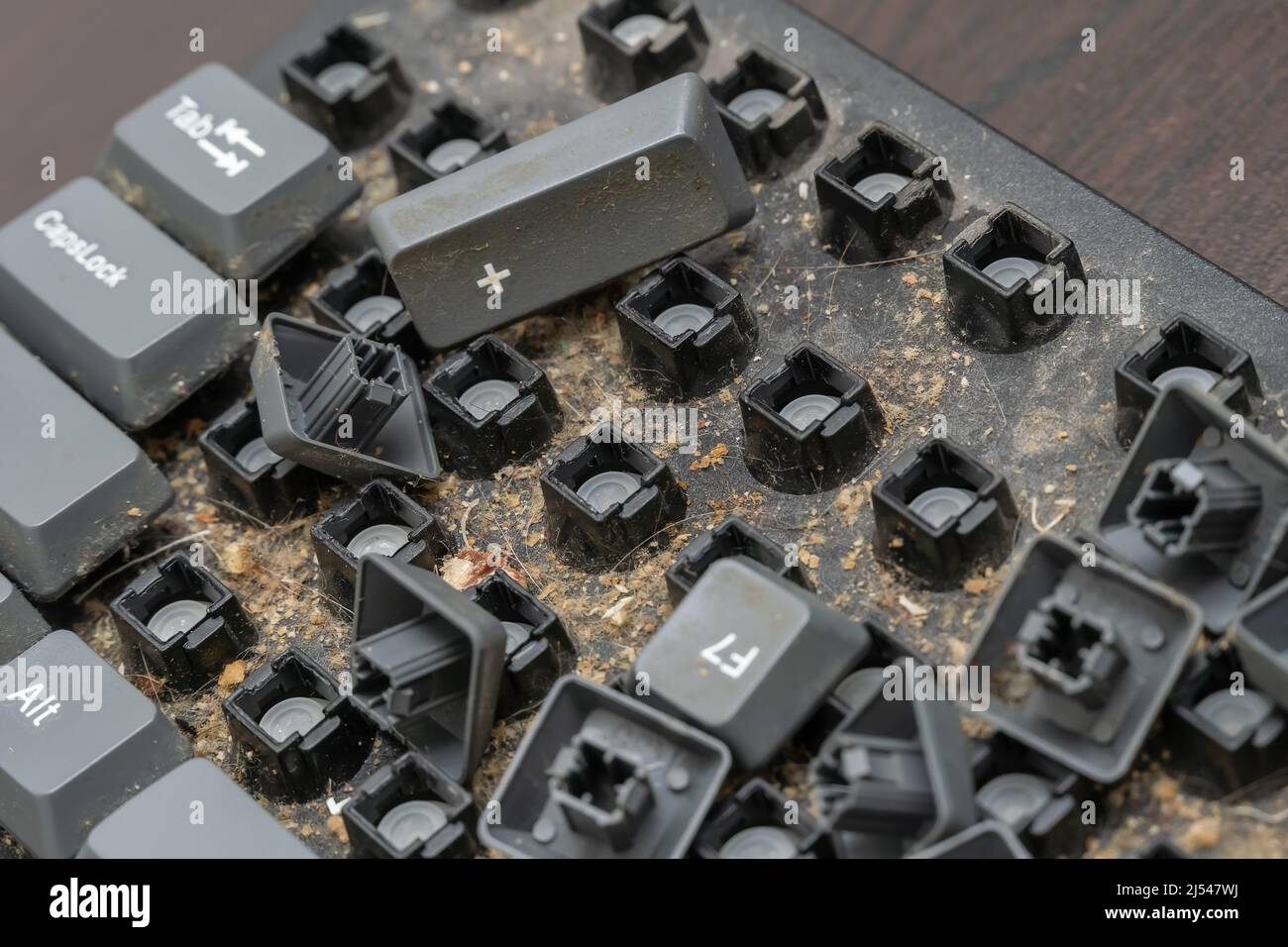 Close-up of a very dirty disassembled computer keyboard on the table. Disassembling a computer keyboard with your own hands, cleaning the keyboard Stock Photo