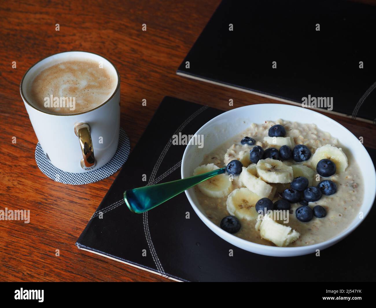 Close-up still life of a bowl of porridge with blueberries and bananas and a mug of coffee Stock Photo