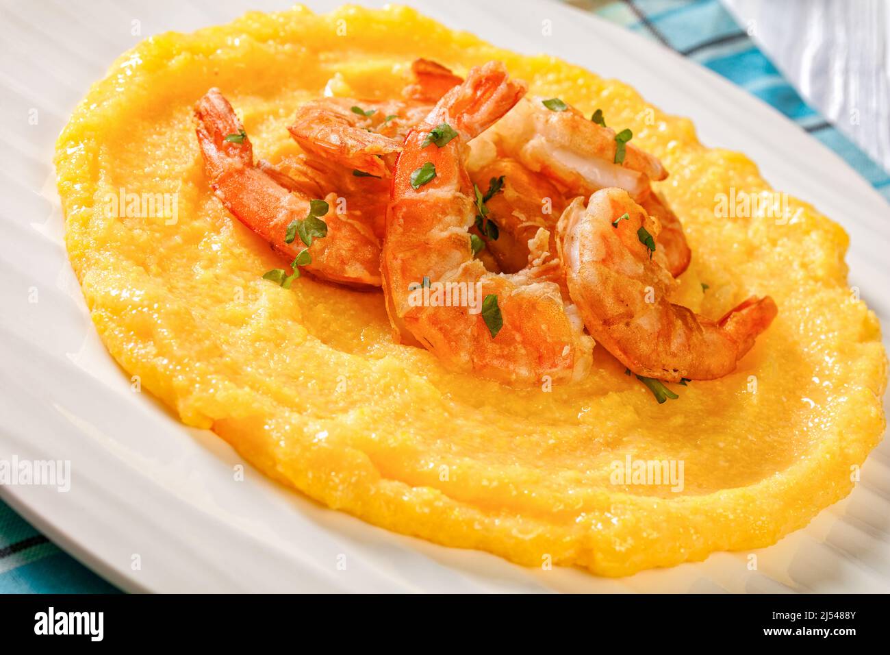close-up of Polenta e schie fritte, venetian cuisine, polenta with fried shrimps on white plate on textured wooden table Stock Photo