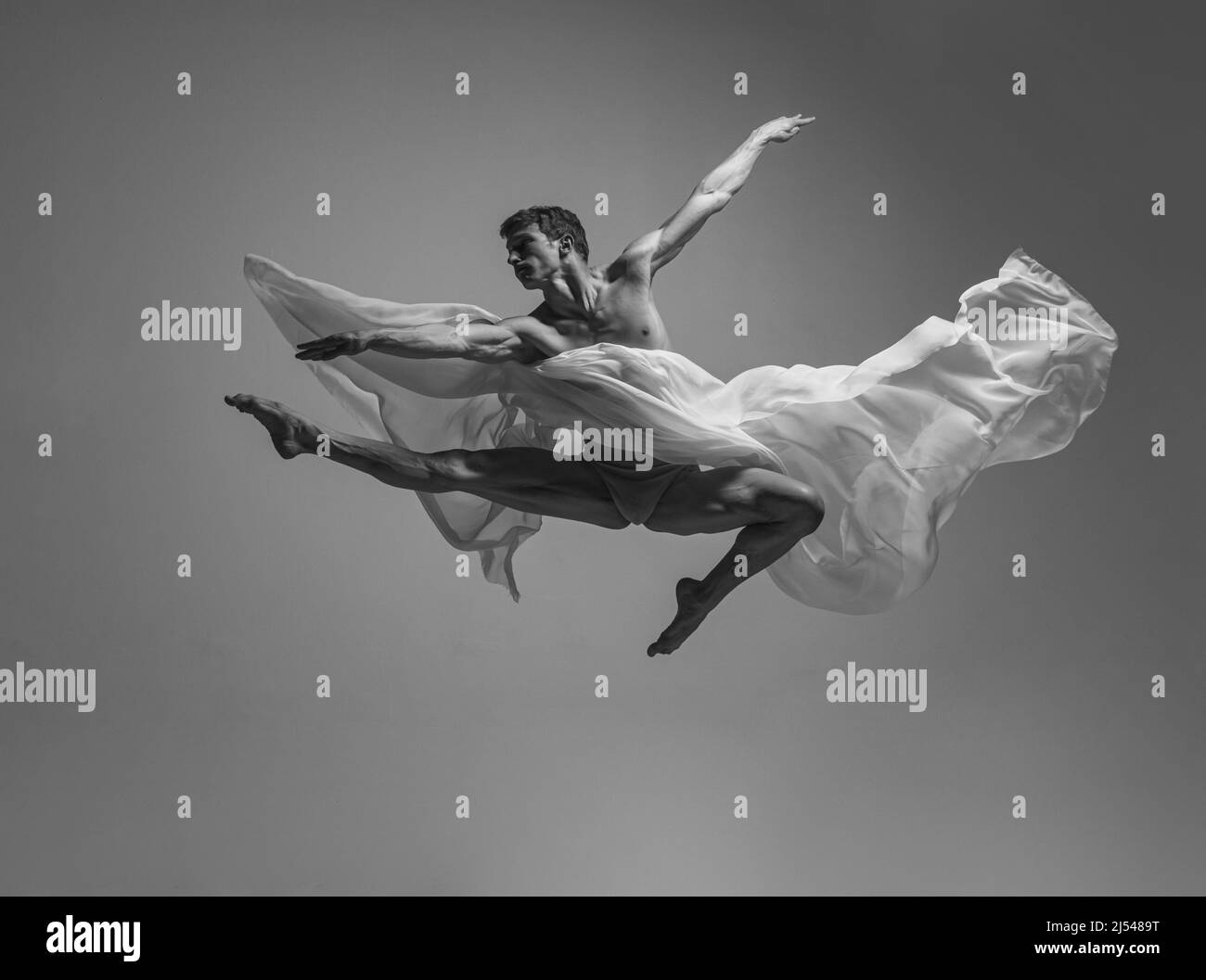 Black and white portrait of graceful muscled male ballet dancer dancing