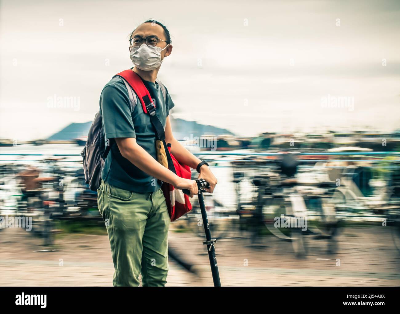 A man riding an electric scooter along a street not looking where he is going.  The background is blurred. Stock Photo