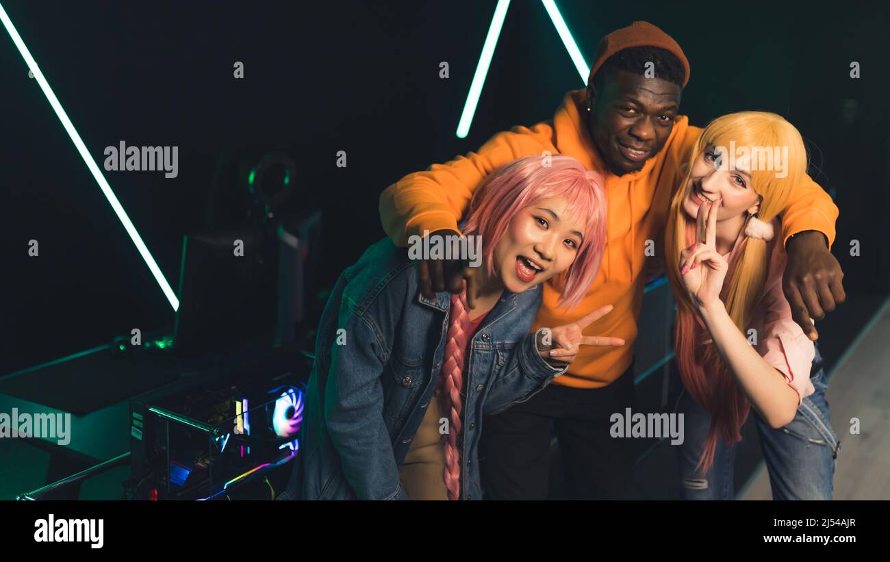 Three interracial young adults in casual wear standing, looking at camera, and smiling. Teammates are about to play a game together in an Internet cafe. Modern leisure time. High quality photo Stock Photo