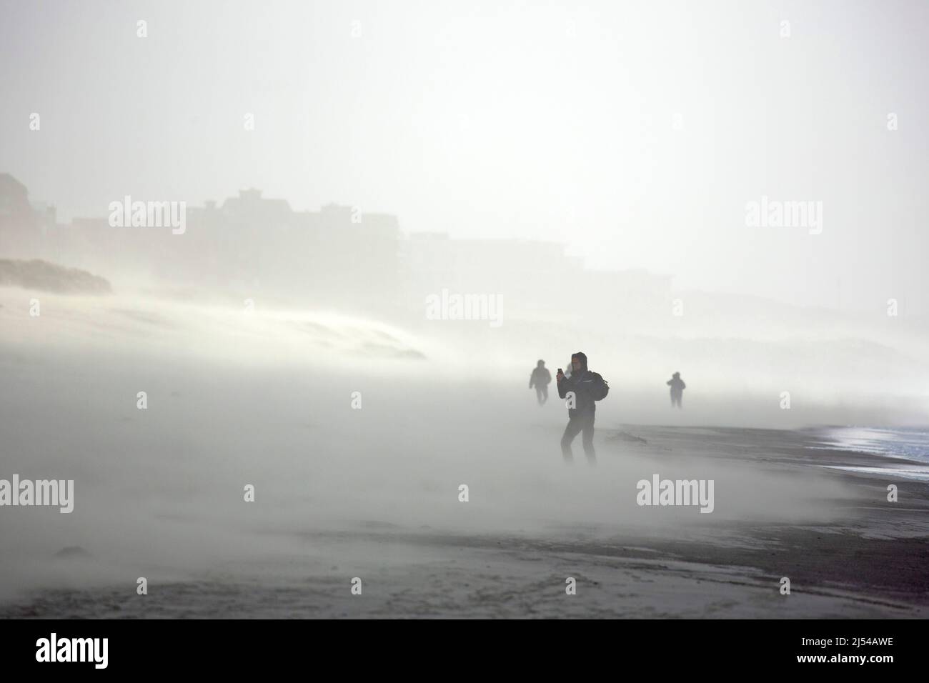walkers in the storm on the sandy beach, Hurricane Eunice, Zeynep, 02/18/2022, Belgium, West Flanders, Nieuwpoort Stock Photo