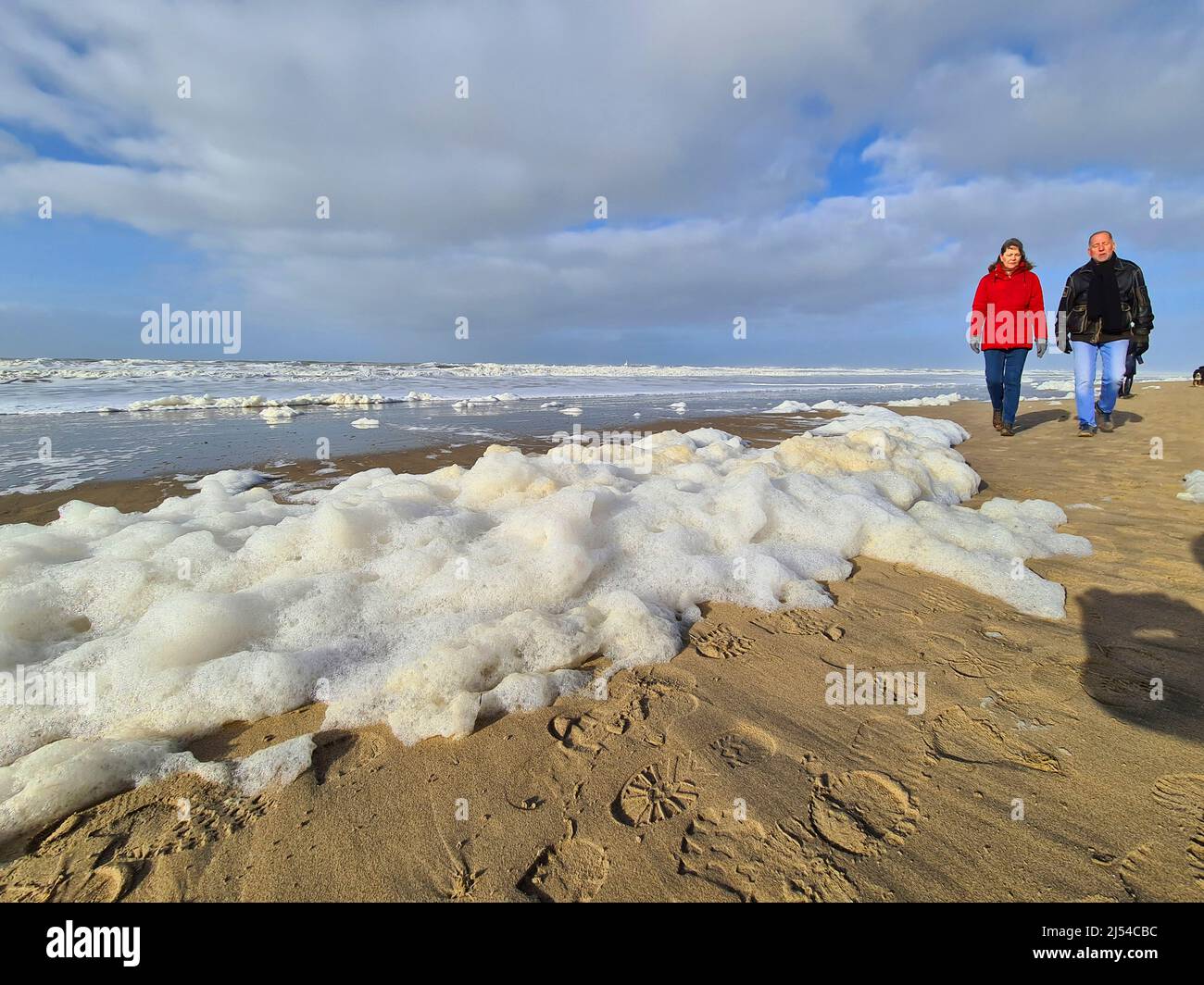 Sea froth at the coast of the North Sea and amblers, Netherlands, Noordwijk aan Zee Stock Photo
