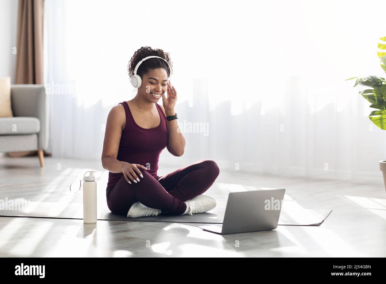Athletic black woman with headset sitting in front of laptop Stock Photo