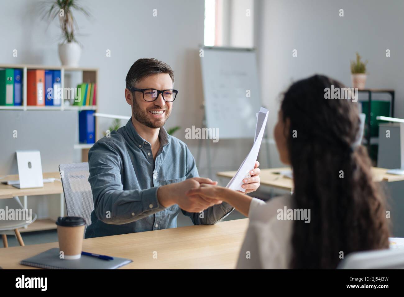 Happy personnel manager and female job applicant shaking hands after