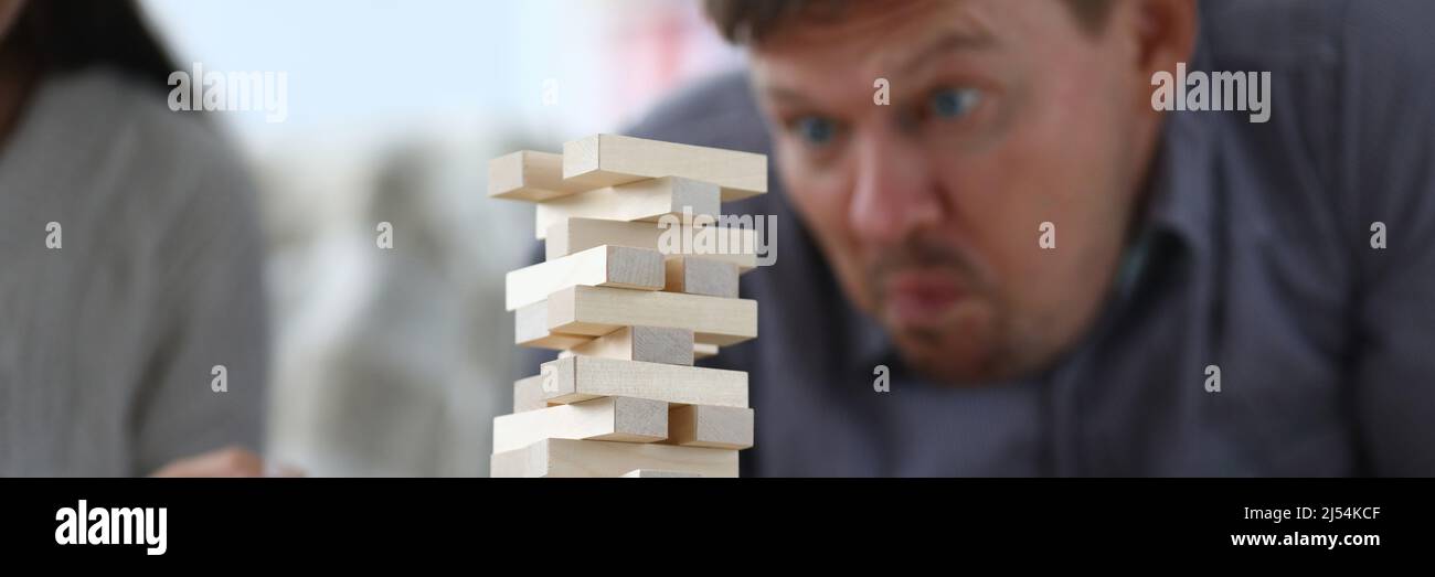 Man assembles a tall tower from wooden rectangular blocks Stock Photo ...