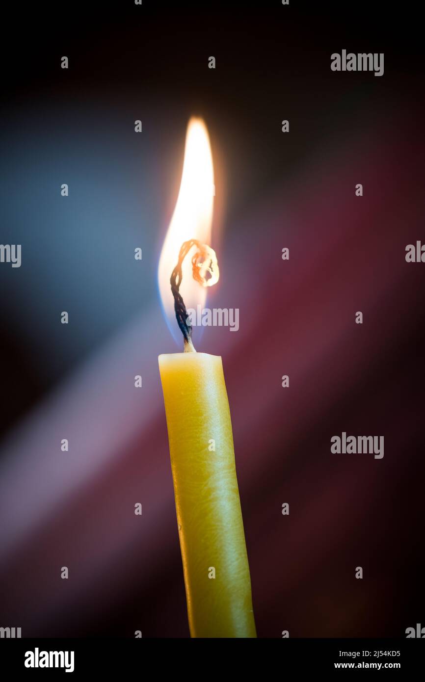 Yellow candle flickering against dark background Stock Photo Alamy