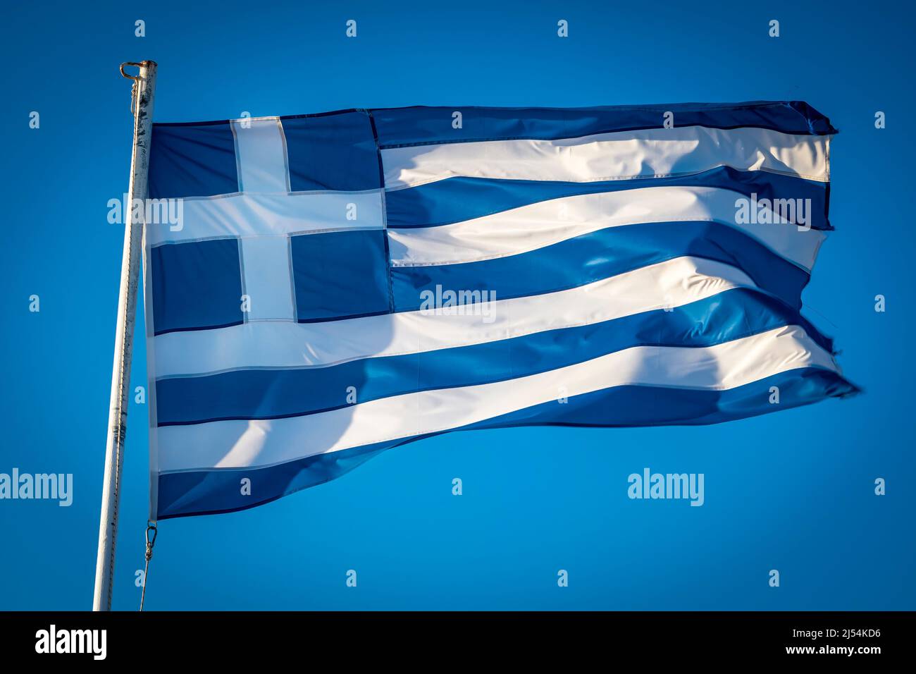 Greek flag fluttering in sunshine against blue sky Stock Photo