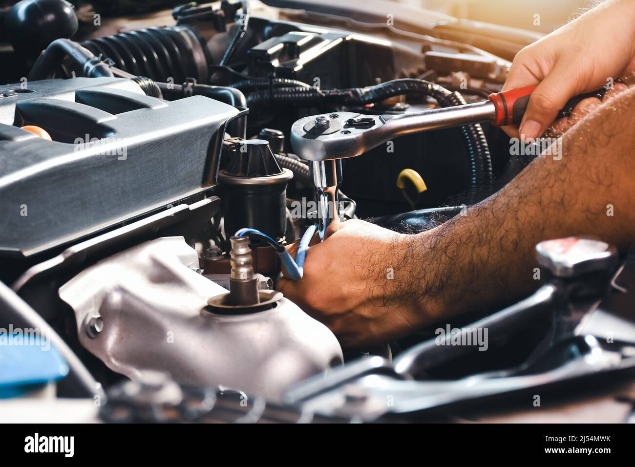 The auto mechanic is fixing the engine of the car with a socket wrench Stock Photo