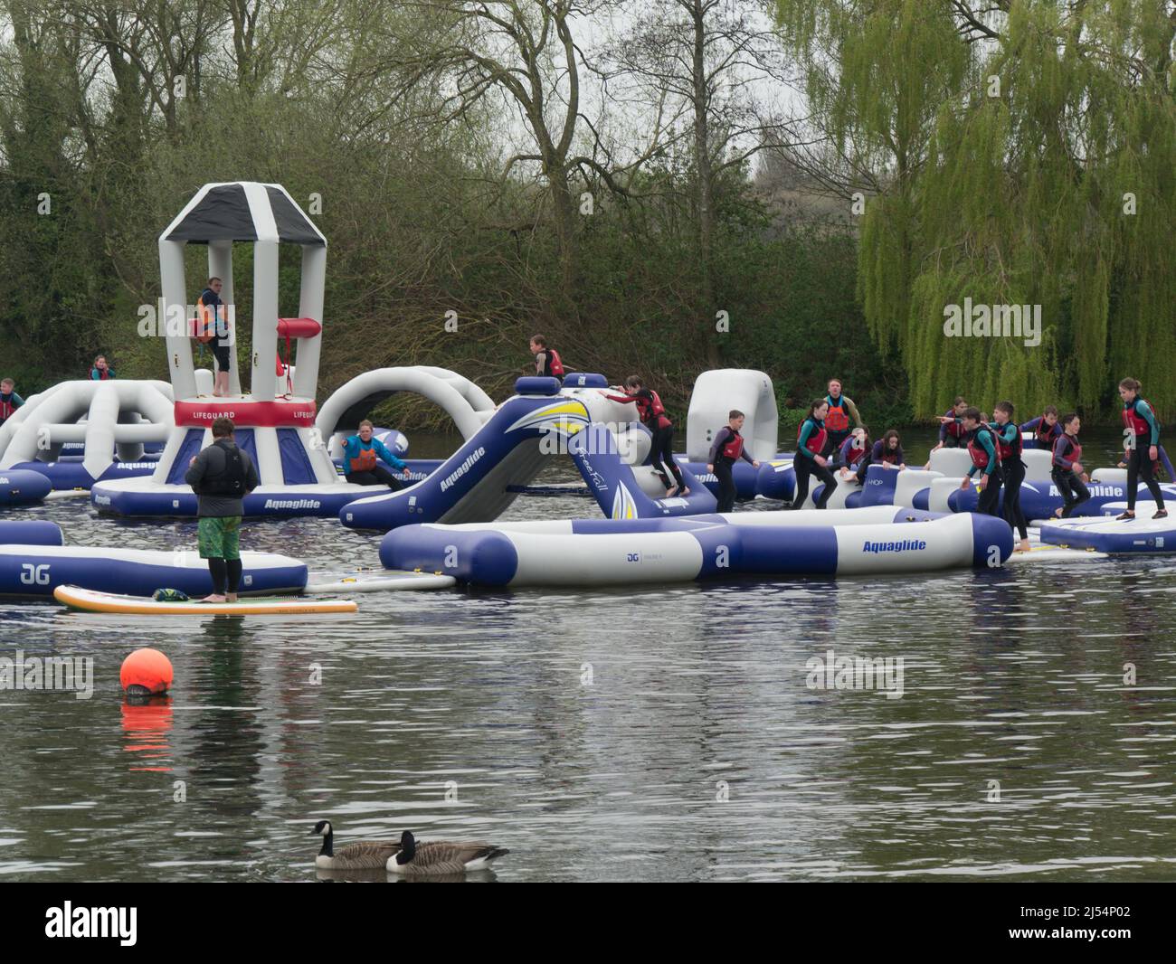 Group of schoolchildren enjoying Lagoon Wipeout inflatable obstacle course beams demolition balls humps basher Holme Pierrepont Country Park Stock Photo