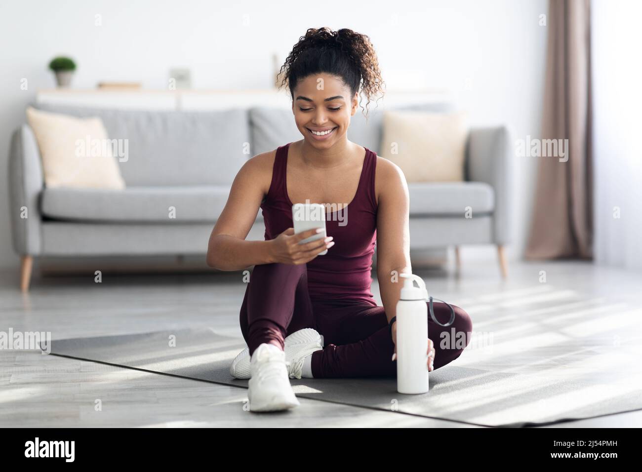 Happy athletic black woman using mobile phone while exercising Stock Photo