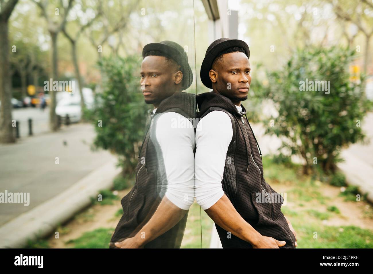 Portrait of a young black male standing against a window shop Stock Photo