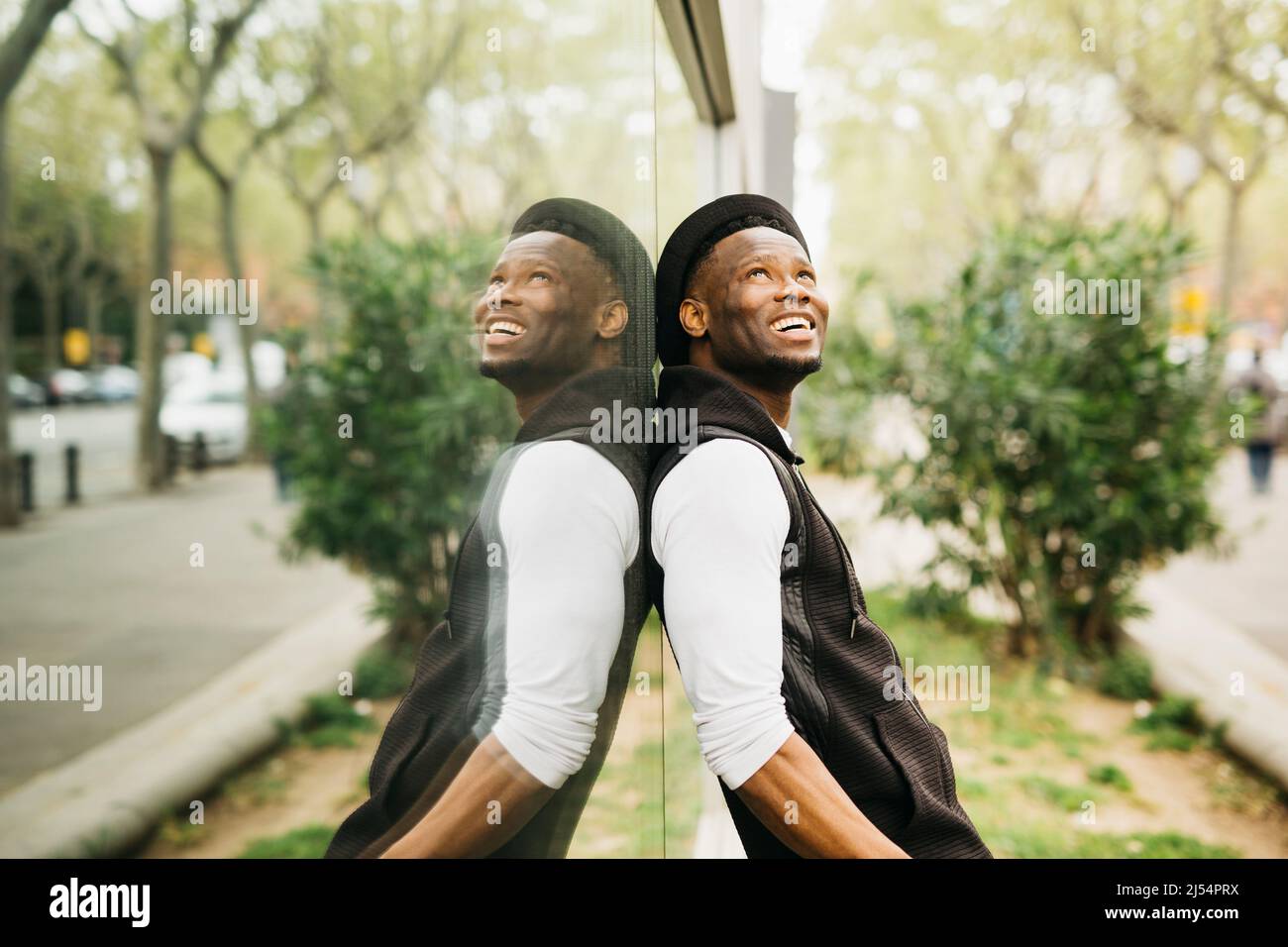 Portrait of a young black male standing against a window shop Stock Photo