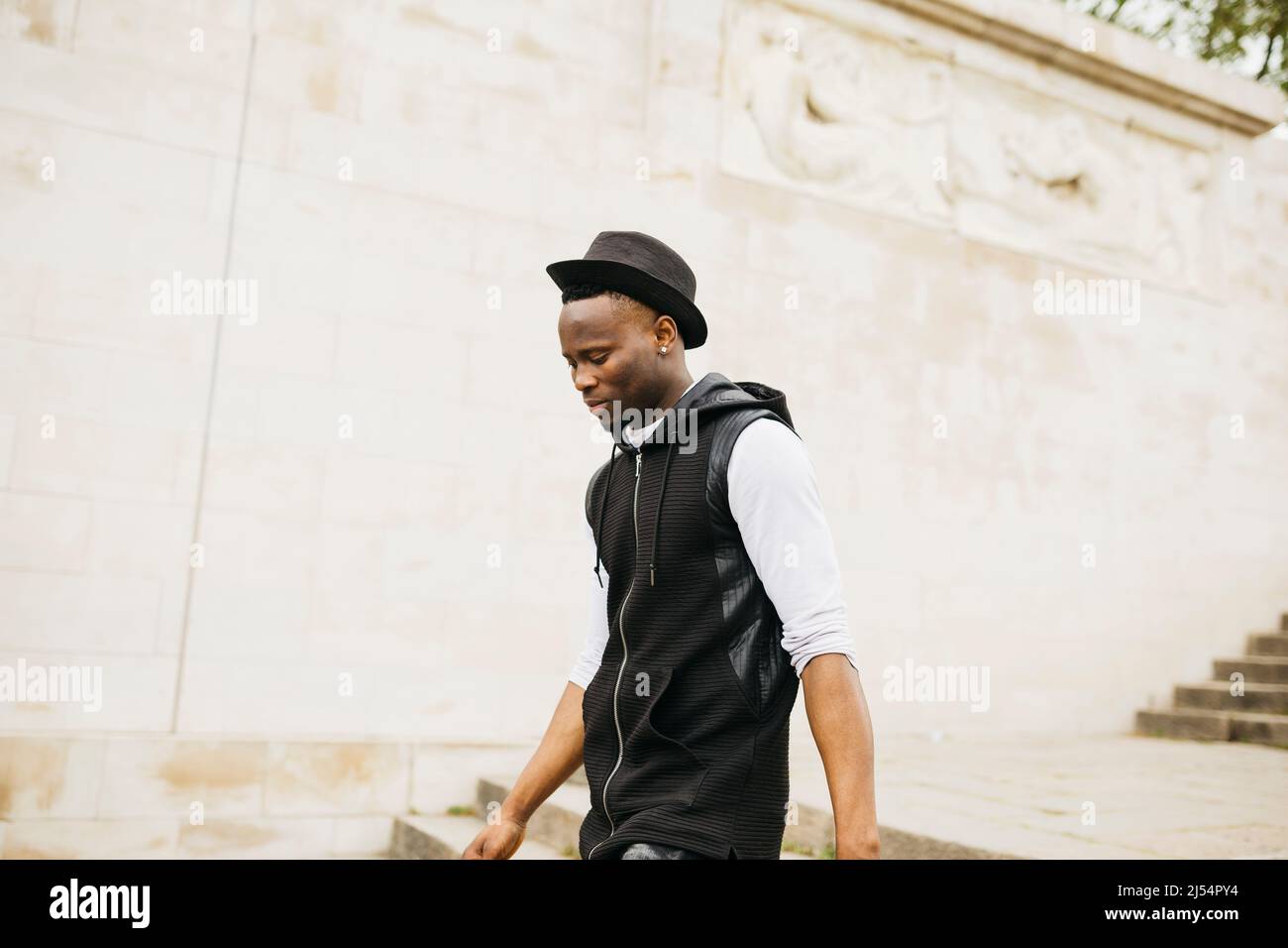 Young black male wearing a black hat walking down stairs on the street Stock Photo