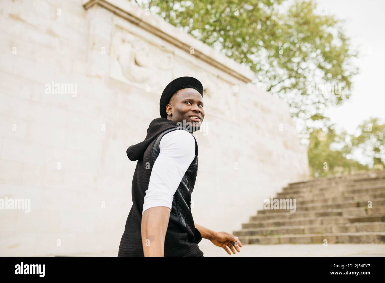 Young black male walking wearing a black hat up stairs on the street Stock Photo