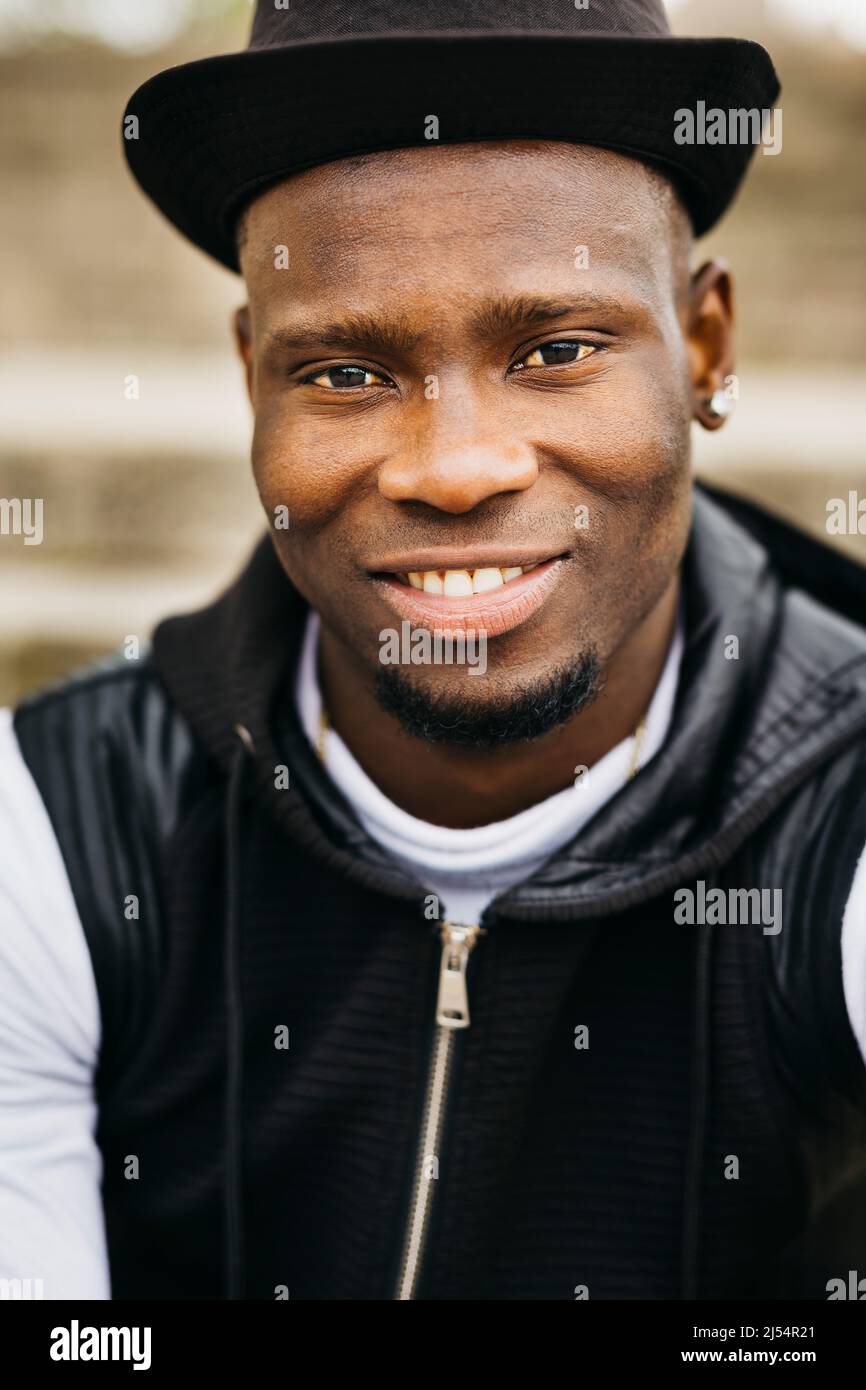 Portrait of a smiling handsome young black male wearing a black hat Stock Photo