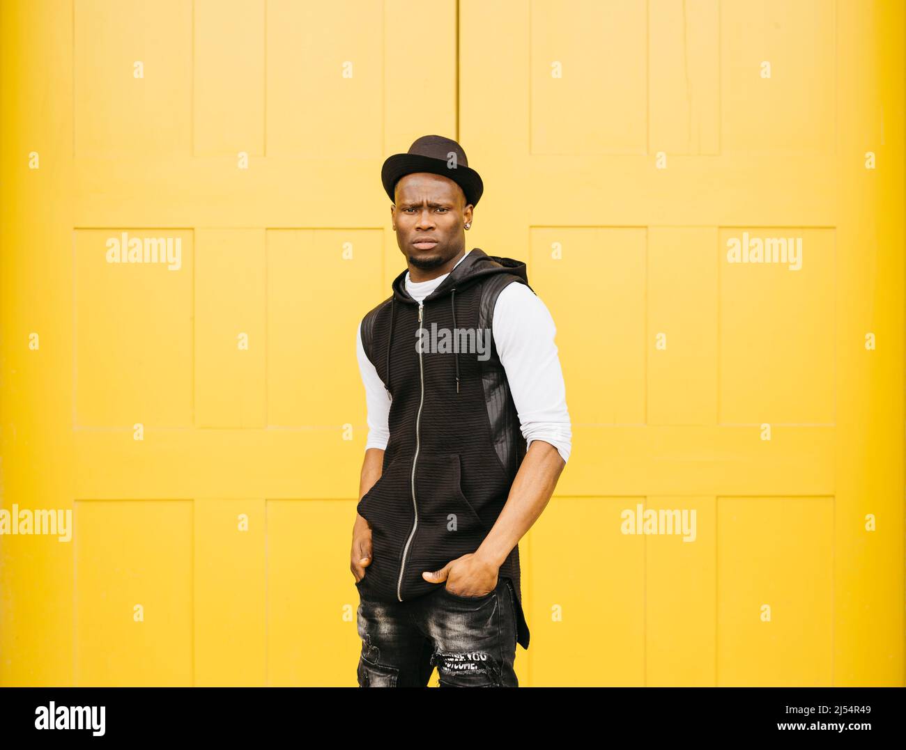 Portrait of a young black male standing against a yellow door Stock Photo
