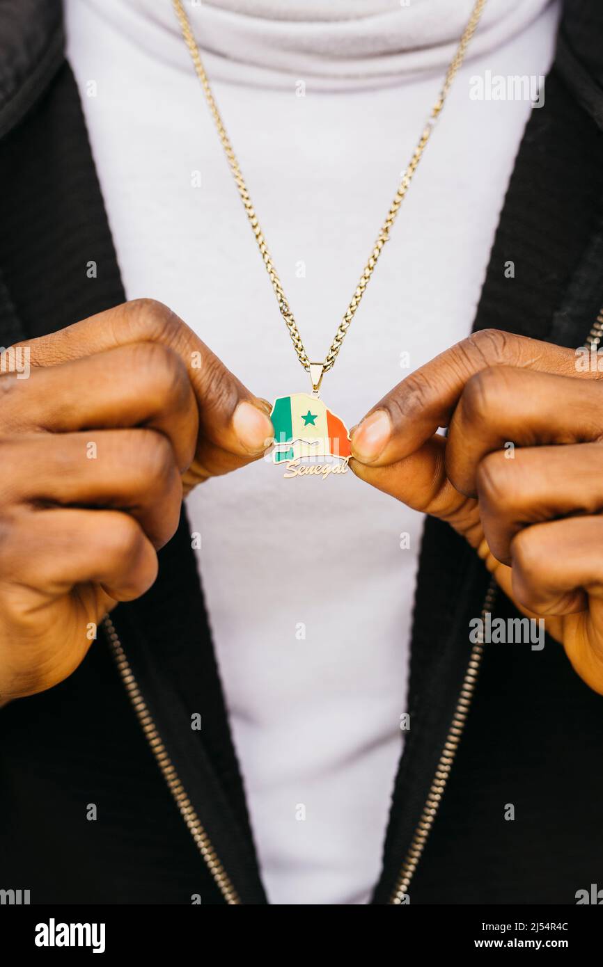 Close up of a Senegal shaped medal with its flag on it holded by a black male Stock Photo