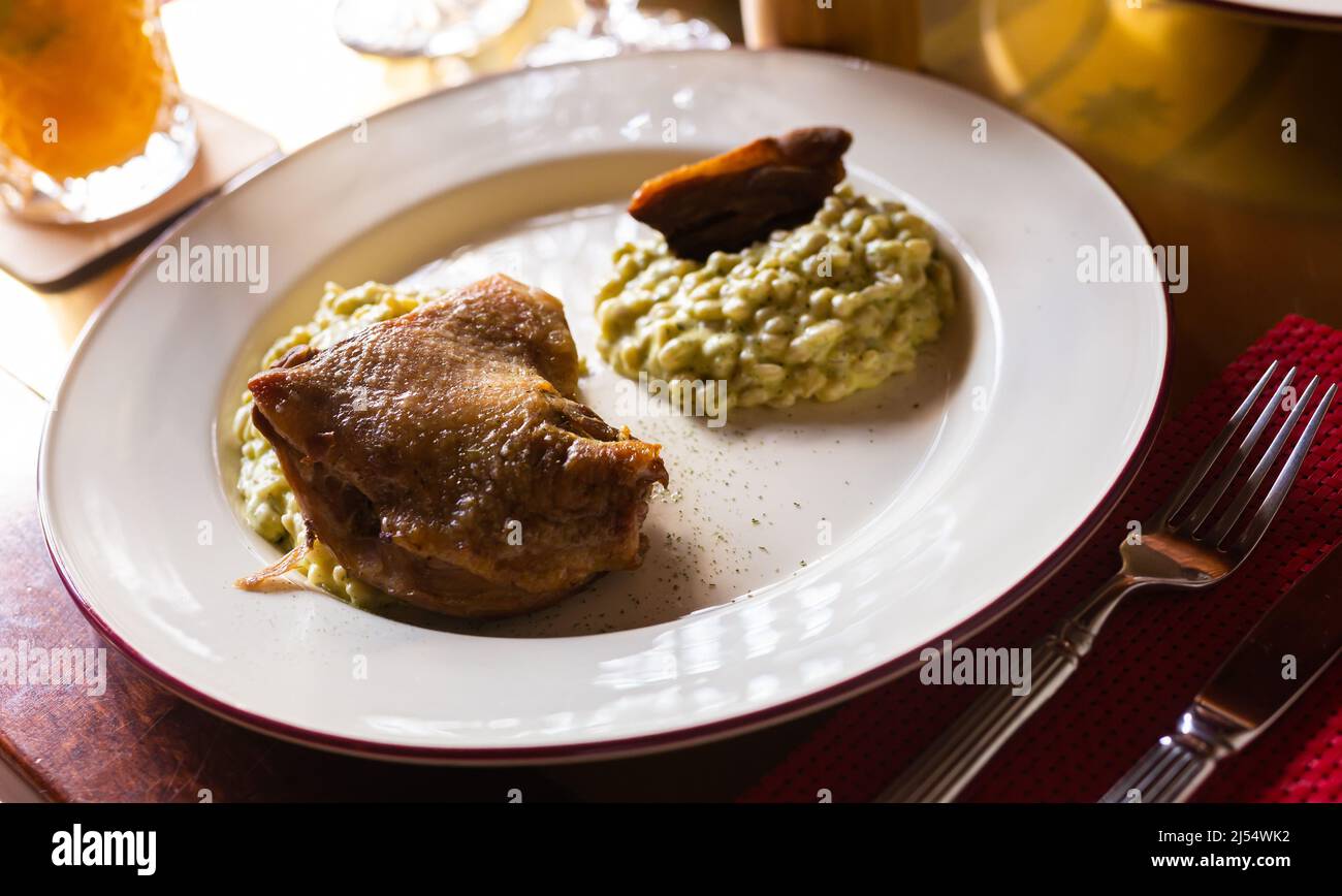 dish duck leg with green perlotto served on a white plate Stock Photo