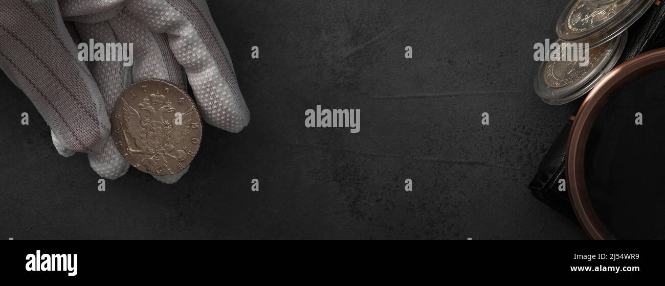 Numismatics. Old collectible coins of silver, gold and copper on the table. A collector in