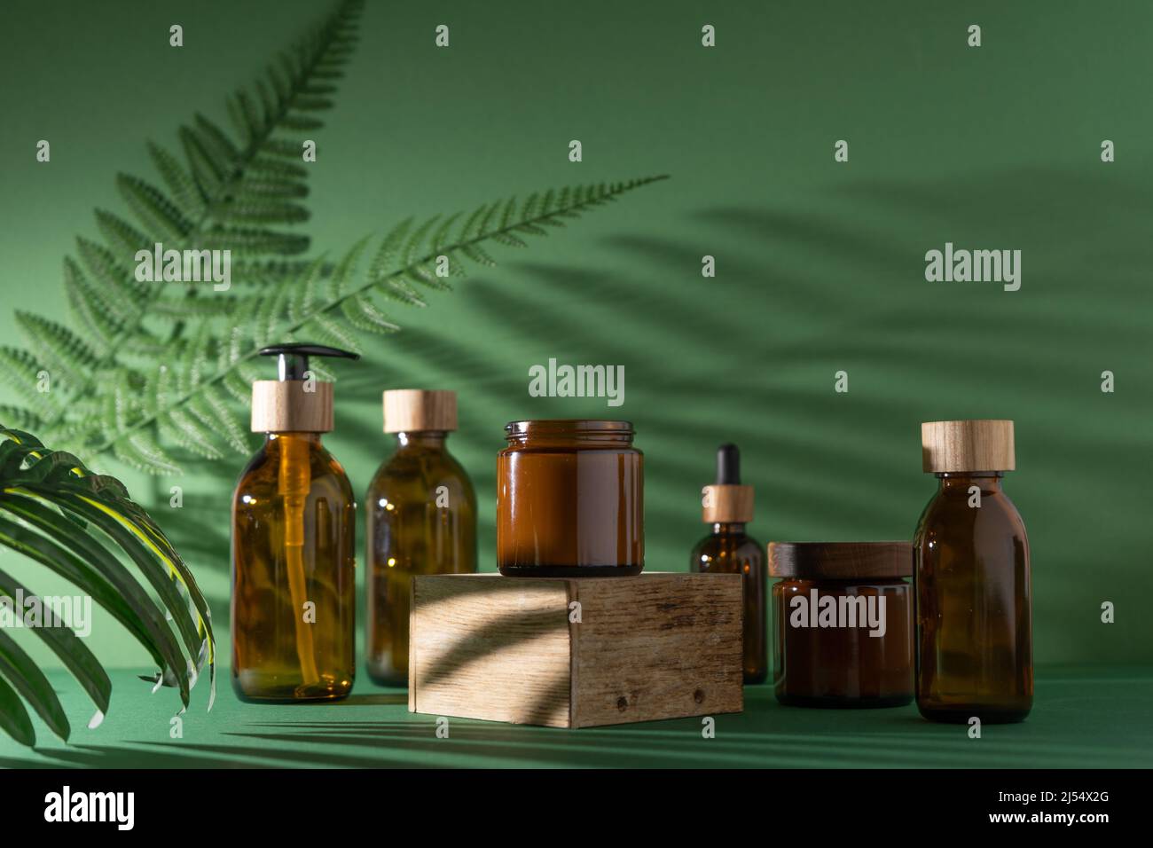 Bottles for cosmetics and cream on a pedestal, green background with ...