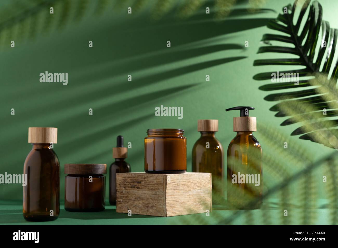 Bottles for cosmetics and cream on a pedestal, green background with ...