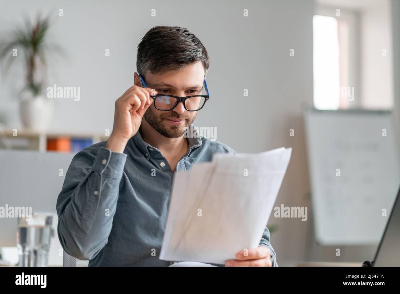 Busy mature male entrepreneur working with papers at workplace in office, checking financial reports Stock Photo