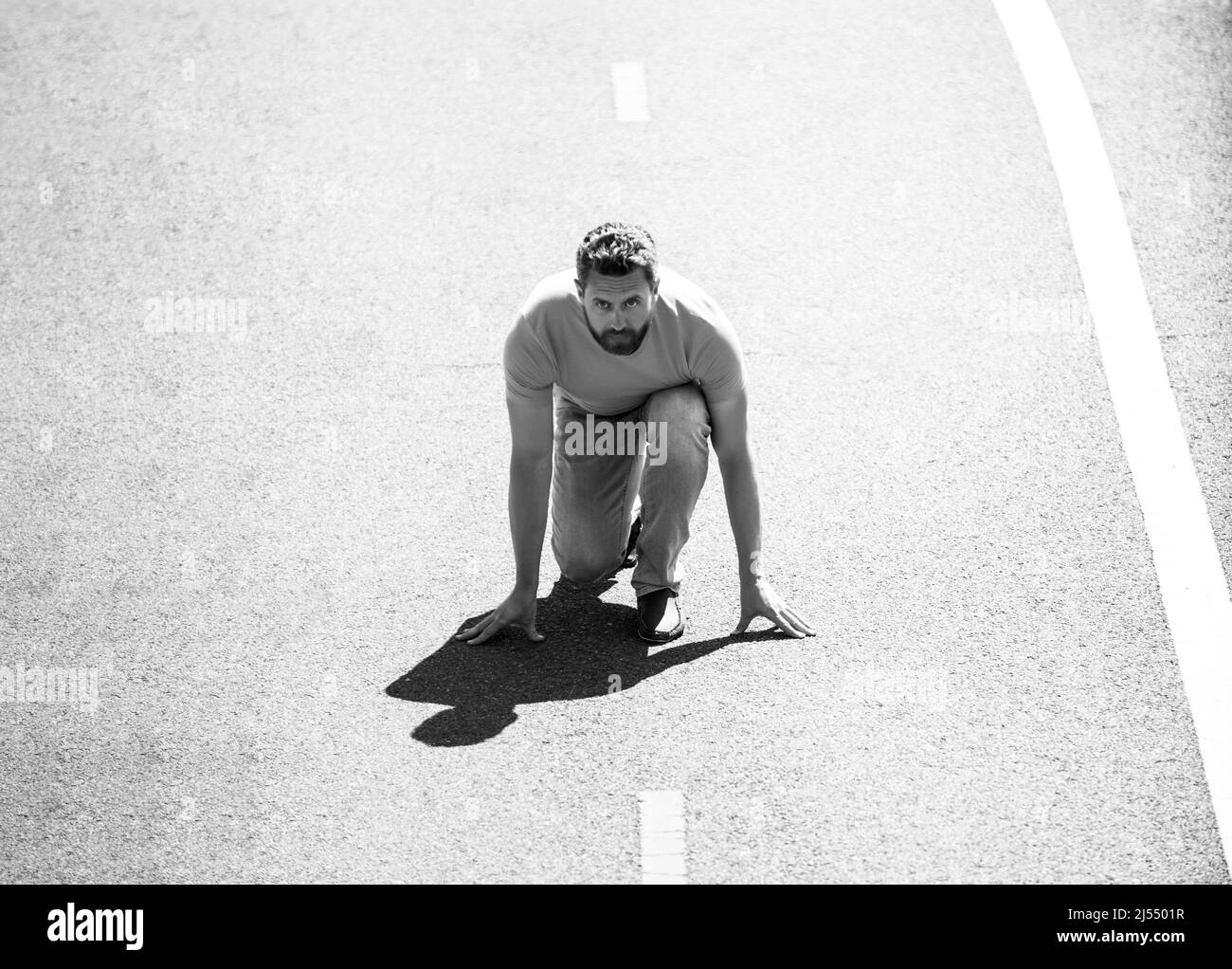 Full length of healthy man running and sprinting outdoors on road. Male runner on start. Stock Photo