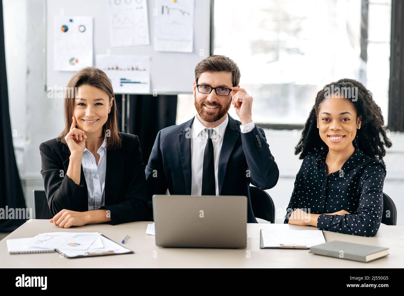 Teamwork, collaboration concept. Multiracial influential business people in formal wear look at the camera, smiling. Elegant creative colleagues sitting in modern office, working together on project Stock Photo