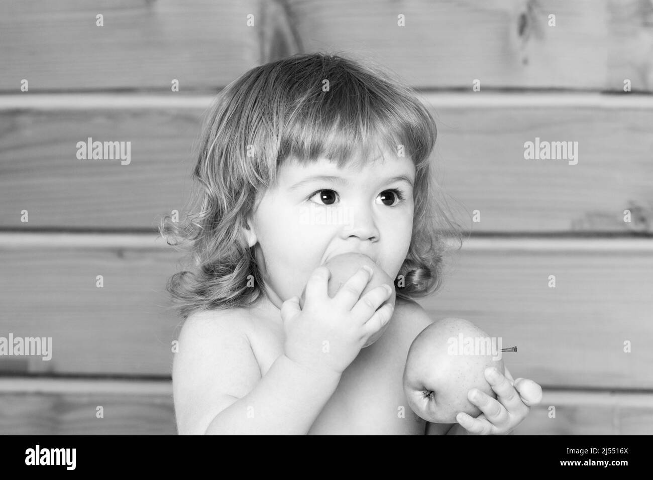 Hungry little baby boy eating apple. Kid with fresh fruit. Stock Photo