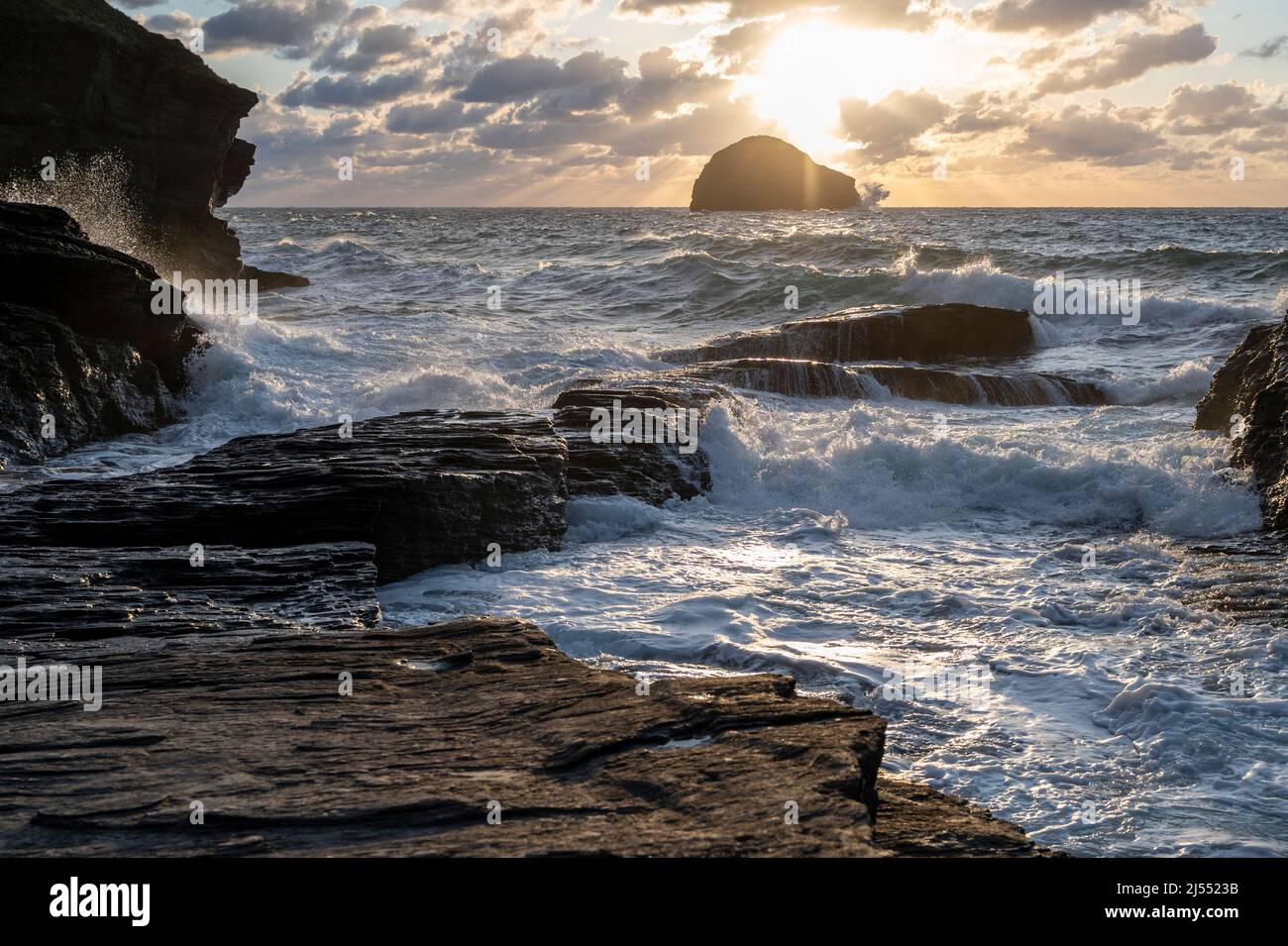 Stormy seas at sunset at Trebarwith Strand, North Cornwall UK, with Gull Rock Island, cliffs and sea spray. Stock Photo