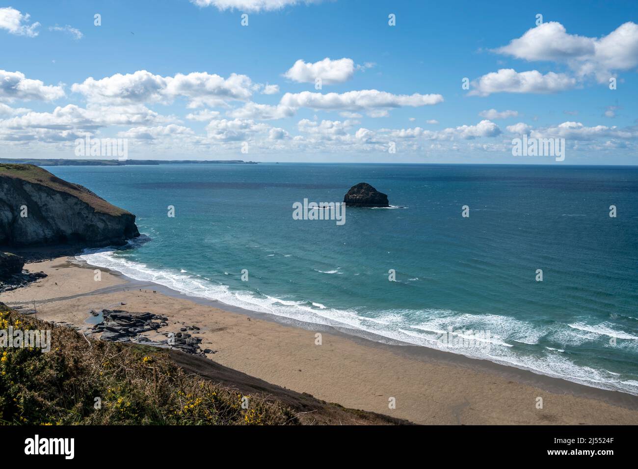 The golden sands of Trebarwith Strand beach, North Cornwall, UK with Gull Rock island, cliffs and turquoise sea. Stock Photo