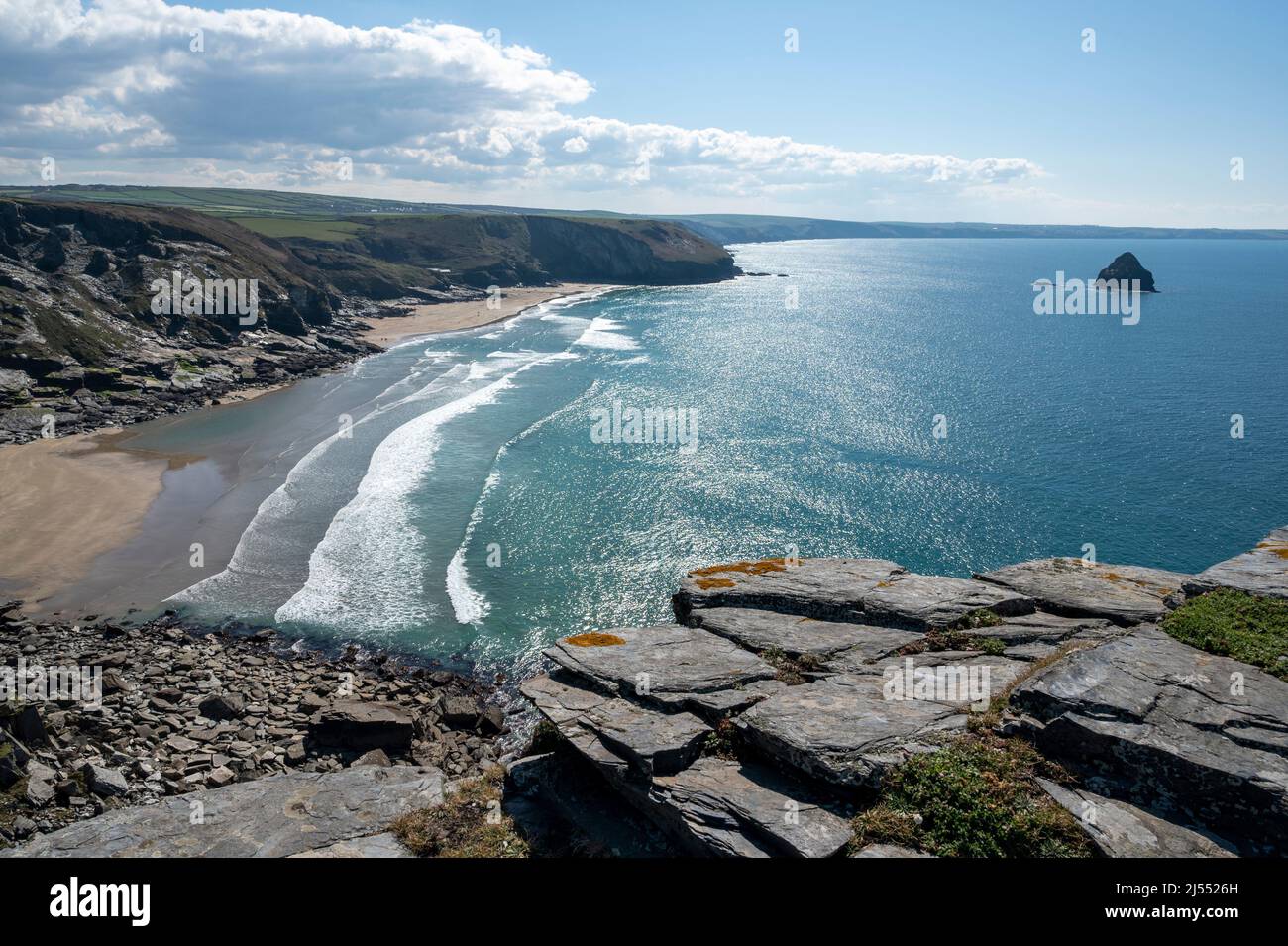 The golden sands of Trebarwith Strand beach, North Cornwall, UK with Gull Rock island, cliffs and turquoise sea. Stock Photo
