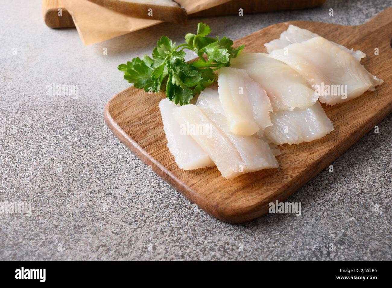 Delicacy fish smoked halibut served with parsley for eating on wooden cutting board. Close up. Rich of healthy omega 3 unsaturated fats. Stock Photo