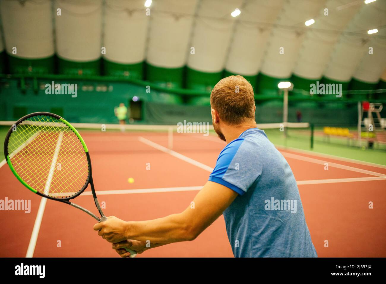 Instructor or coach teaching how to play tennis on a court indoor stock