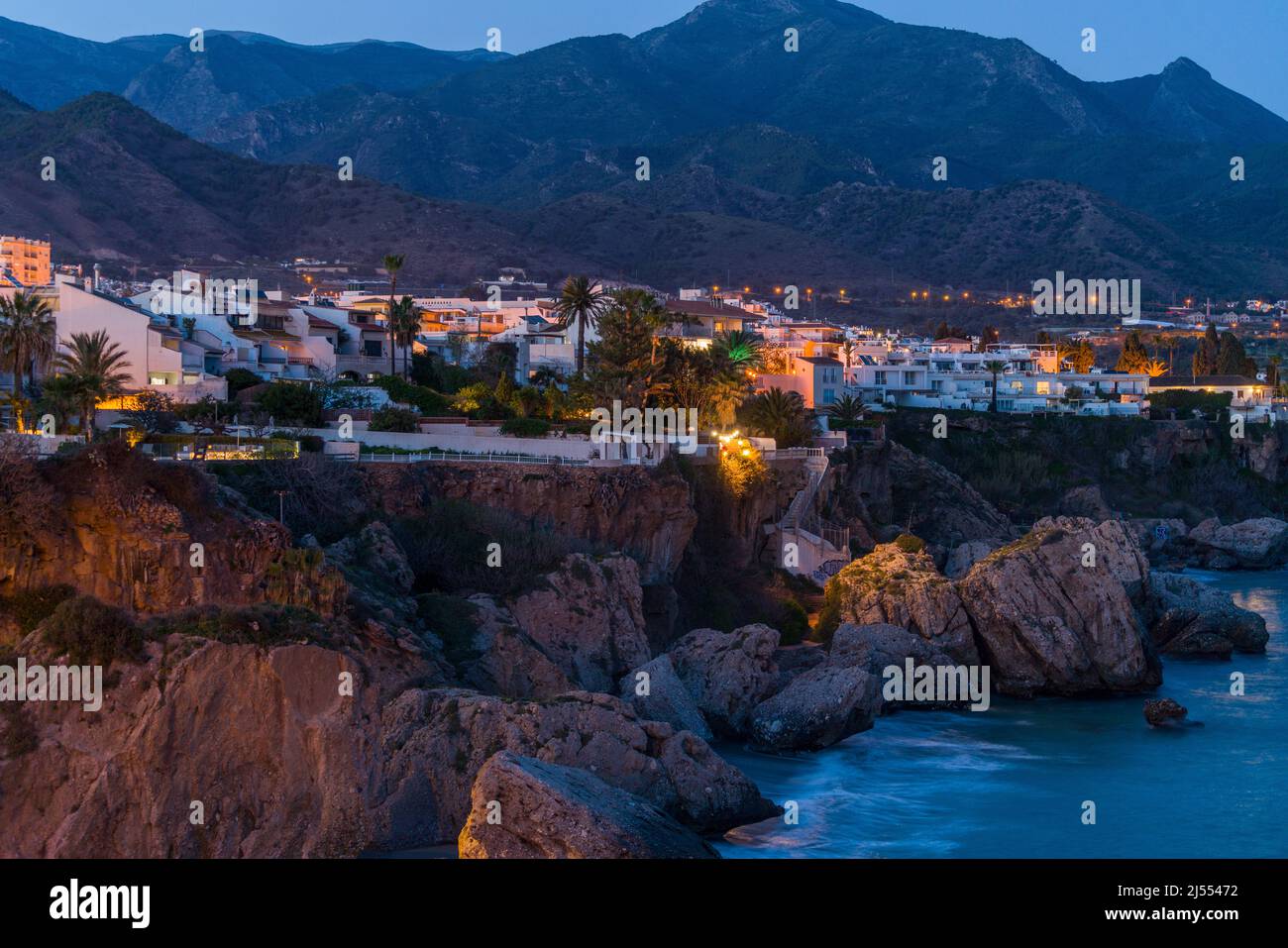 Photography with long exposure of beautiful city of Nerja, Spain by night. View of the coastline with houses illuminated. In background Sierra Nevada Stock Photo