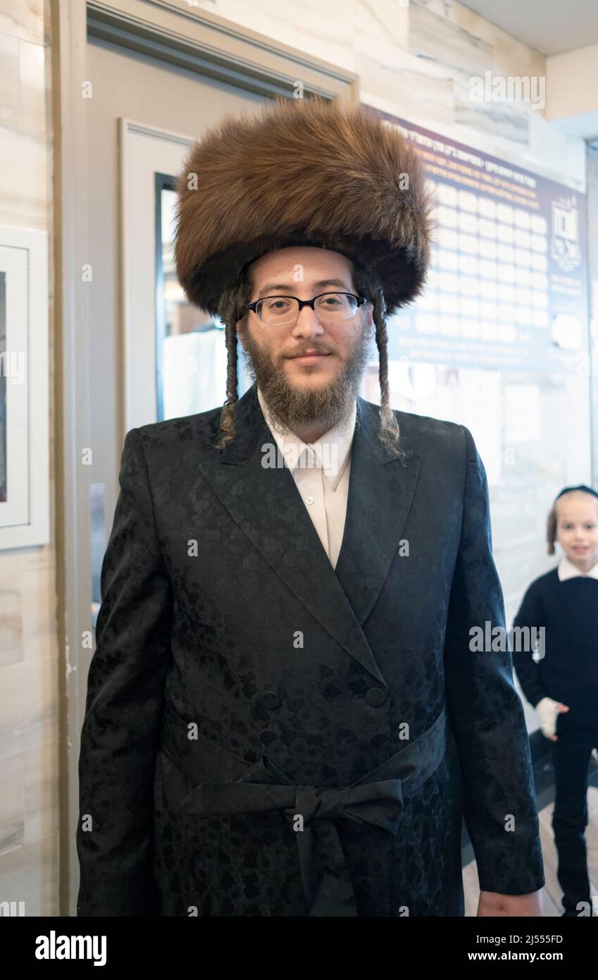 An orthodox Jewish man wearing a shtreimel fur hat while being photobombed by a young boy. In Williamsburg, Brooklyn, New York. Stock Photo