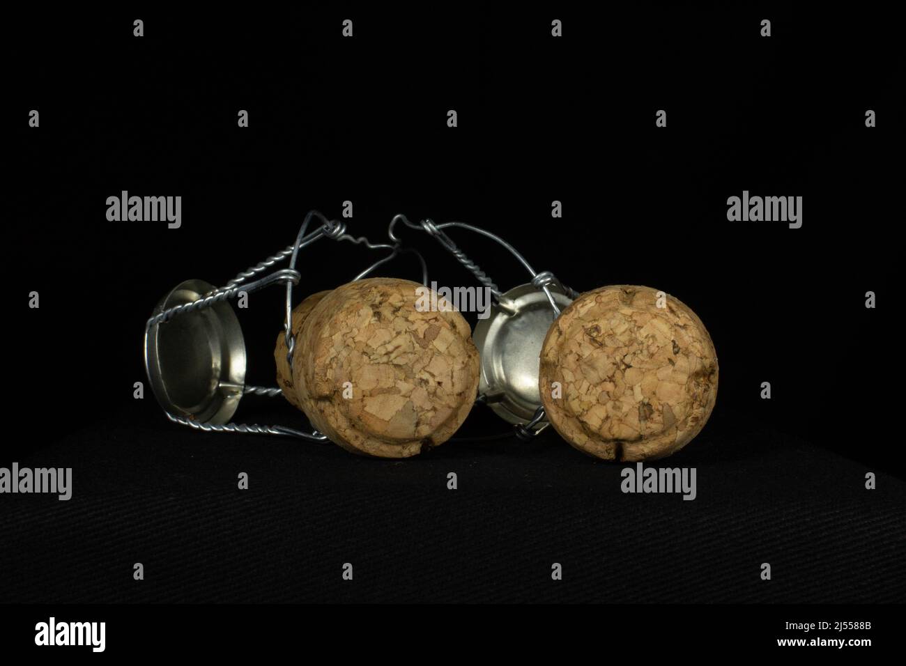 two sparkling wine corks and wire cages isolated on a black background