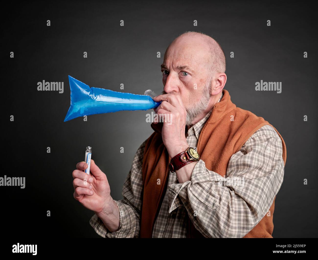 Head and shoulders portrait of a senior man performing breath test to