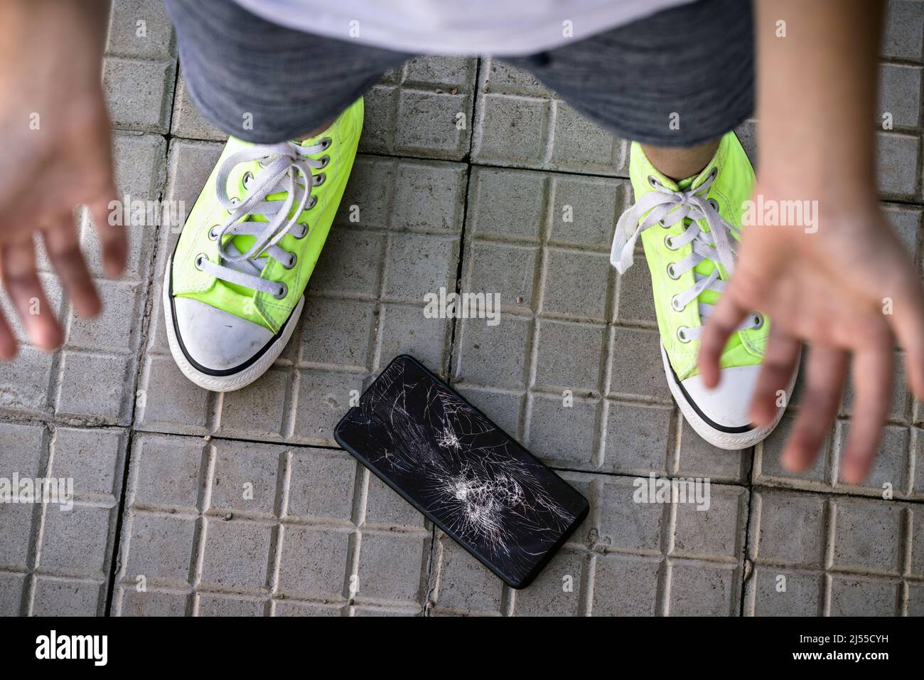 young child breaking cell phone, device dropped on the floor and screen shattered, no concert, careless child, cracked smartphone protective film Stock Photo