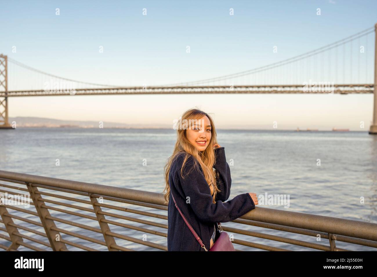 Late Afternoon Half Body Portraits of Young Woman with Oakland Bay Bridge and San Francisco Bay in the Background | Lifestyle Travel To the City Stock Photo
