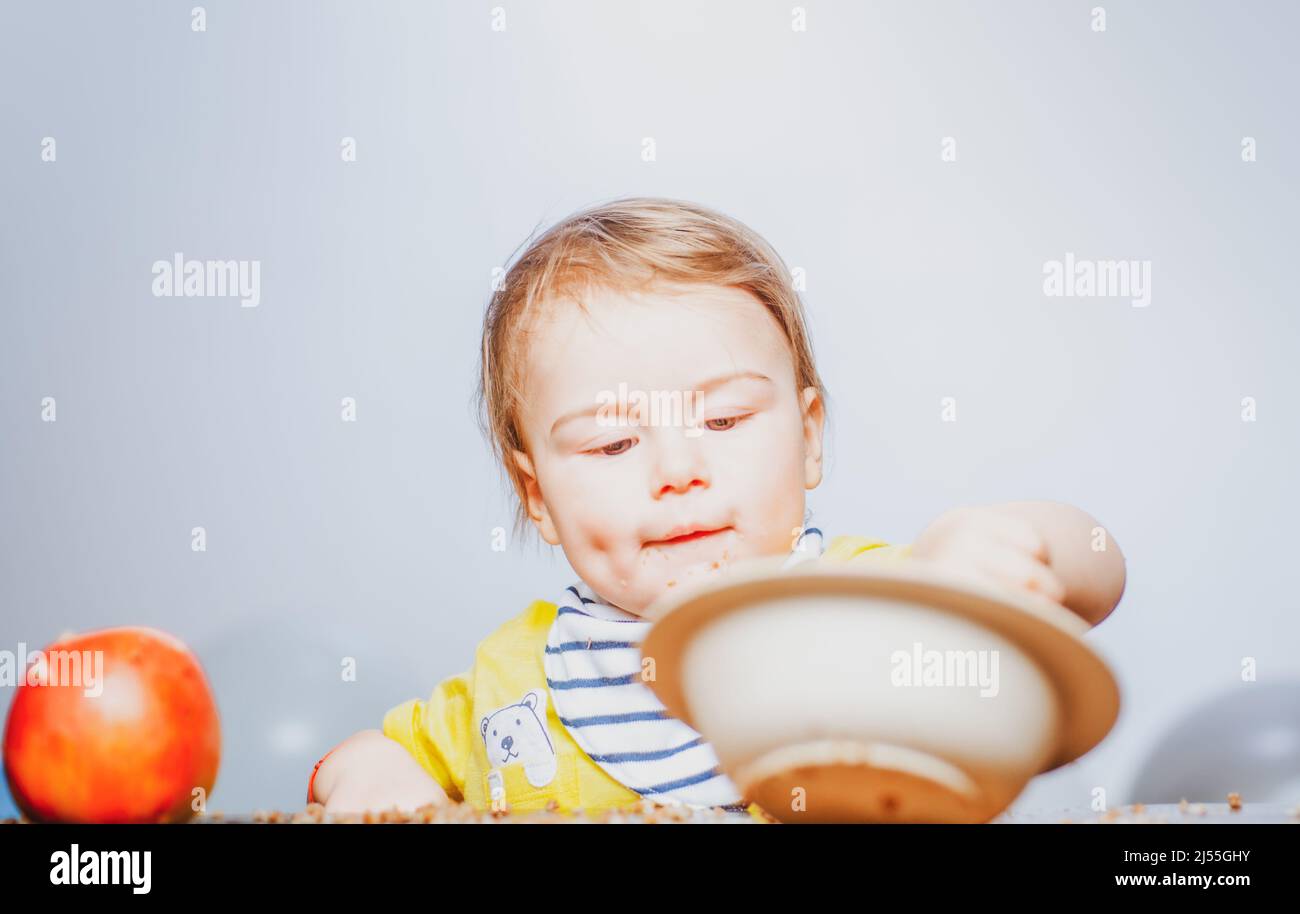 Cute funny babies eating, baby food. Funny kid boy with plate and spoon. Stock Photo