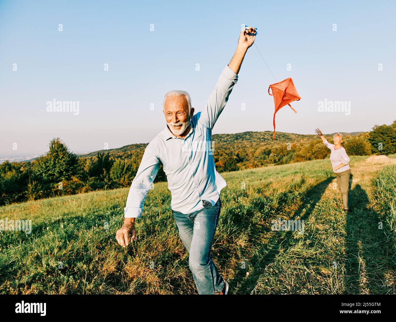 woman man outdoor senior couple happy lifestyle retirement together smiling love kite run nature mature Stock Photo